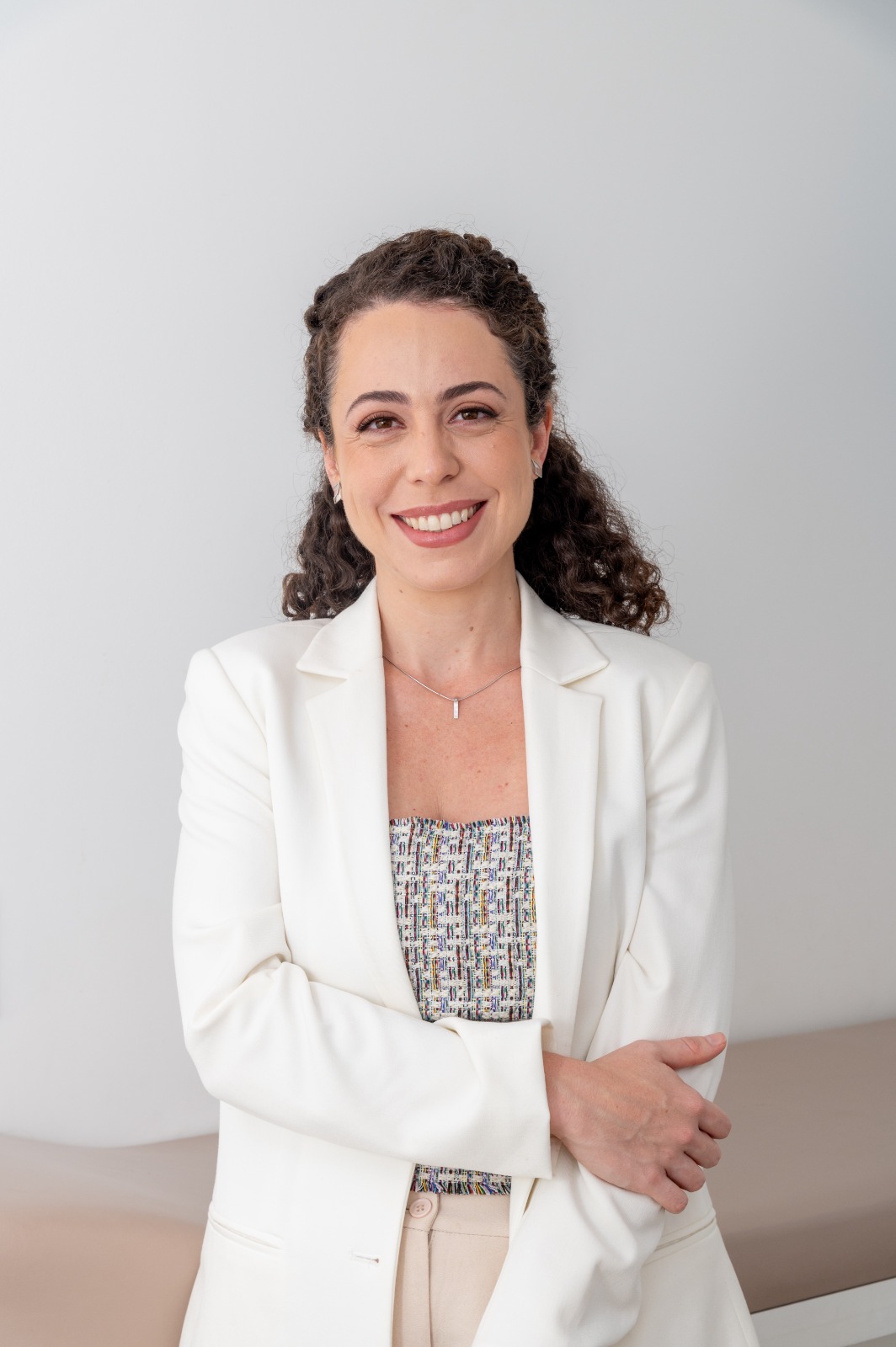 Foto da Dra. Julia Melardi, de jaleco branco, em ambiente claro
